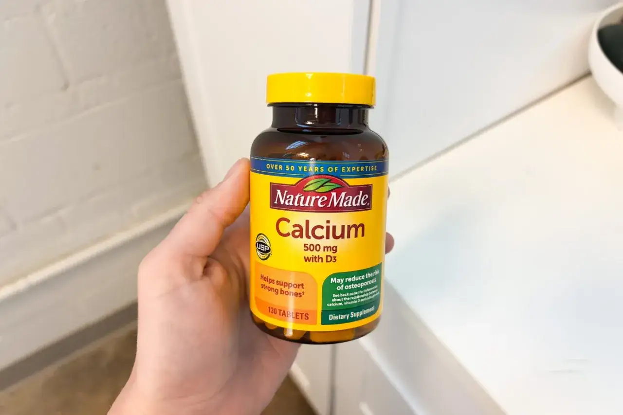 Dłoń trzyma butelkę suplementu Nature Made Calcium 500 mg z D3, który pomaga wspierać mocne kości i może zmniejszać ryzyko osteoporozy.
