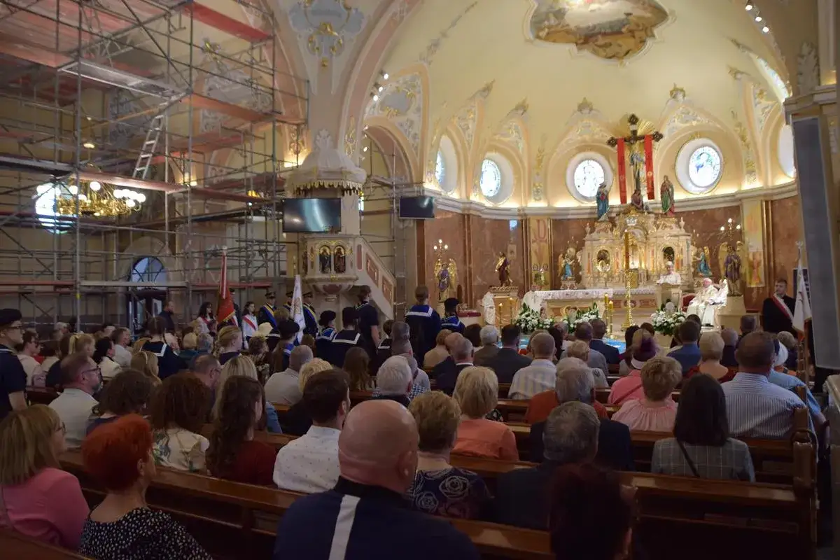 Uroczystość kościelna 3 maja w kościele z wiernymi na ławkach i rusztowaniami po lewej stronie.