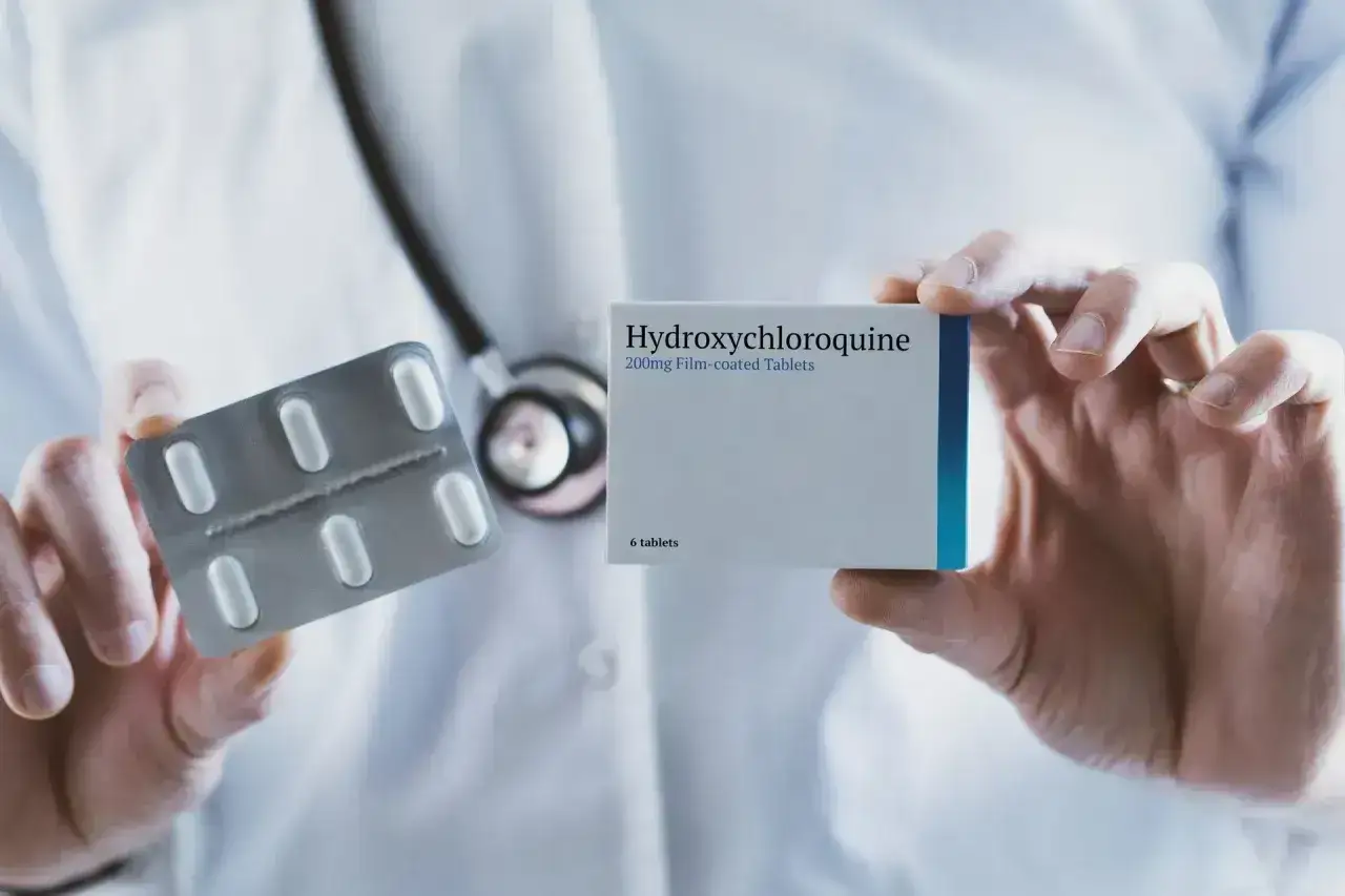 Lekarz trzyma opakowanie i blister z tabletkami Hydroxychloroquine.