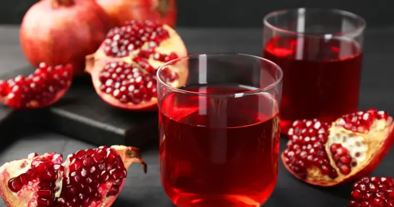 Szklanki z rubinowym sokiem z granatu i świeże owoce. Odkryj sok z granatu właściwości i ciesz się jego smakiem.